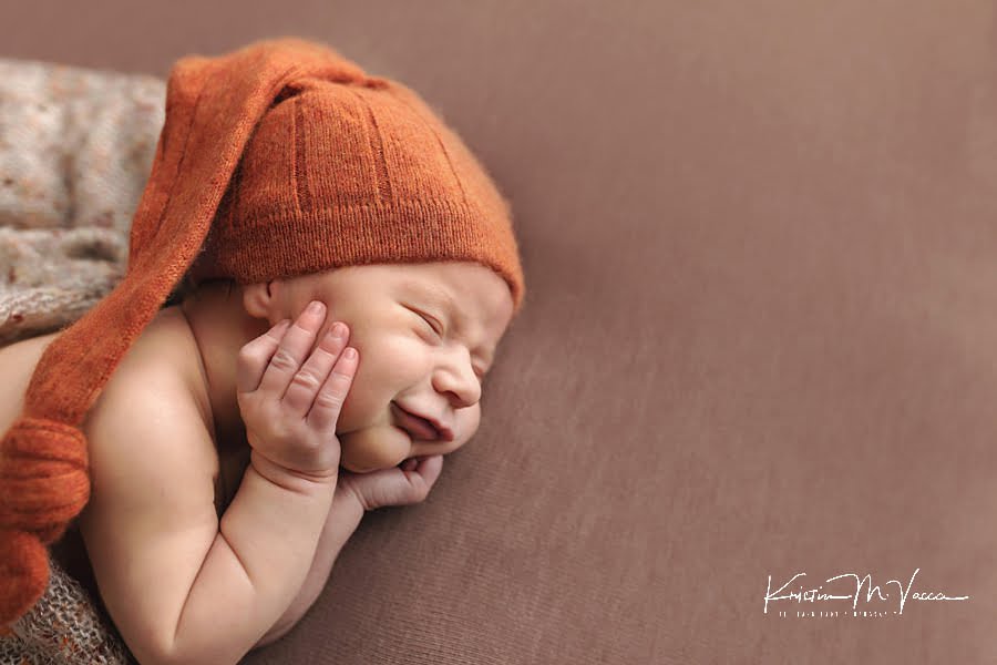 Slow up of sleeping baby boy with his hands on his cheeks during his newborn photos