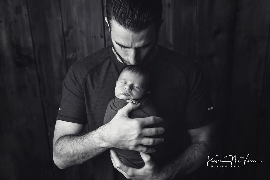 Black and white photo closeup of Dad kissing his son during their photoshoot