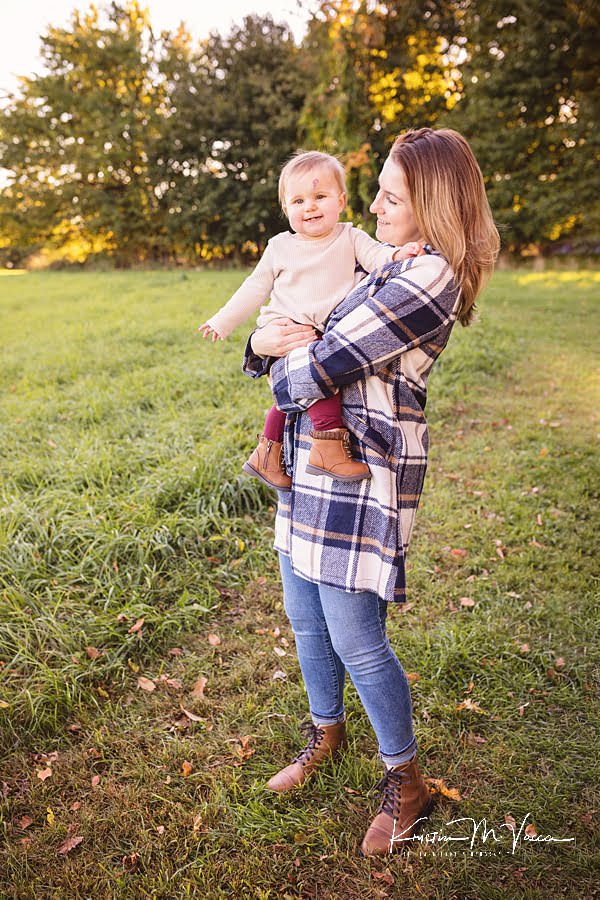 Mom holds her baby girl on her hip during their fall photos