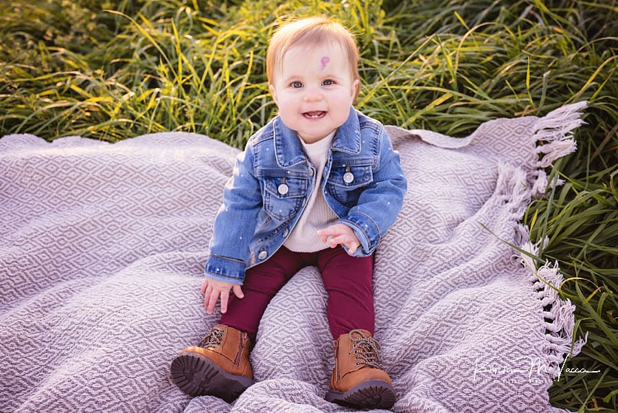 Baby girl sitting up on a blanket and smiling during her family fall photoshoot
