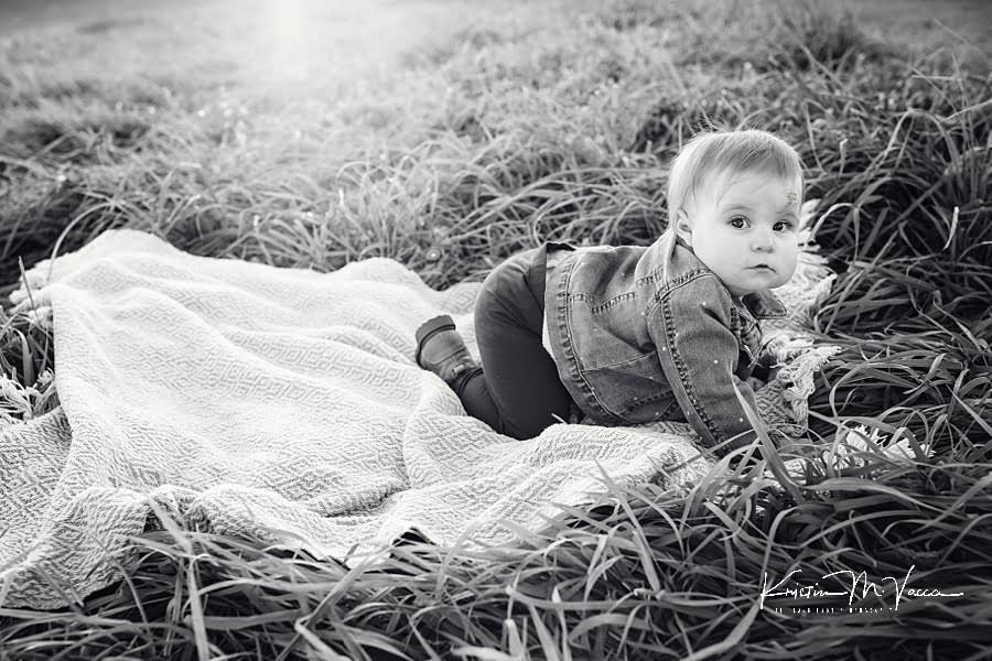 Black and white photo of a baby girl crawling on a blanket during her photoshoot