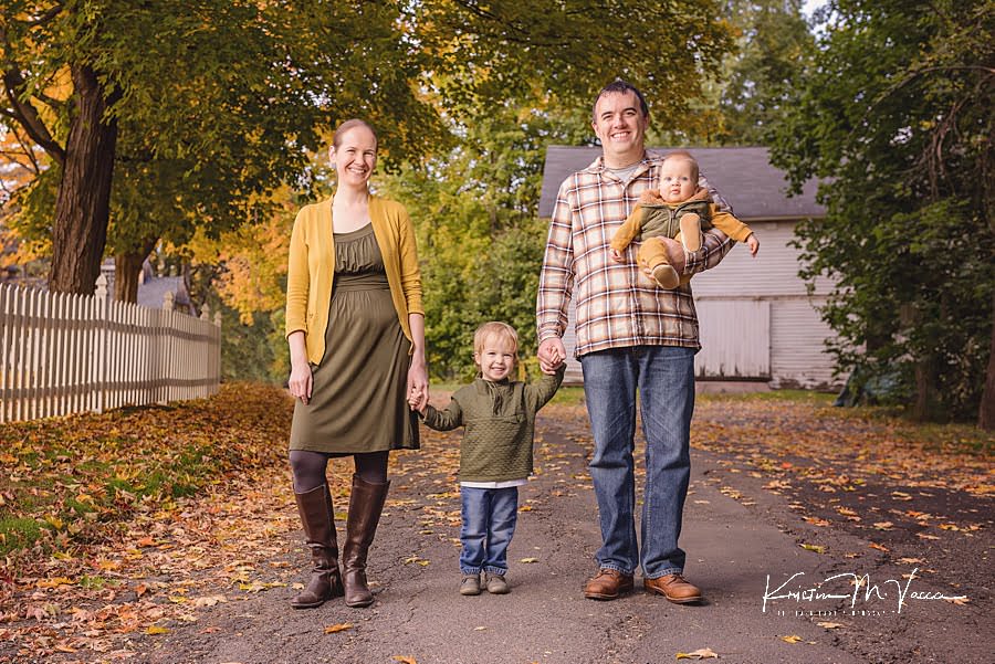 Family of 4 holding hands walking towards the camera during their happy fall family photos