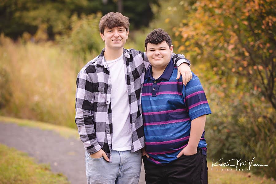2 brothers stand with arms around their shoulders during their twin boy senior photos