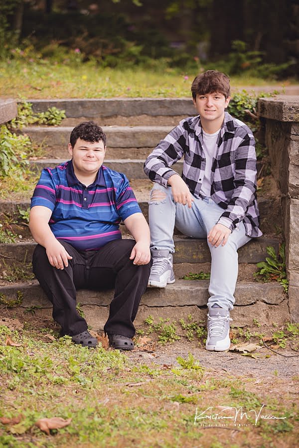 Teen brother sit on stone steps during their twin boy senior photos