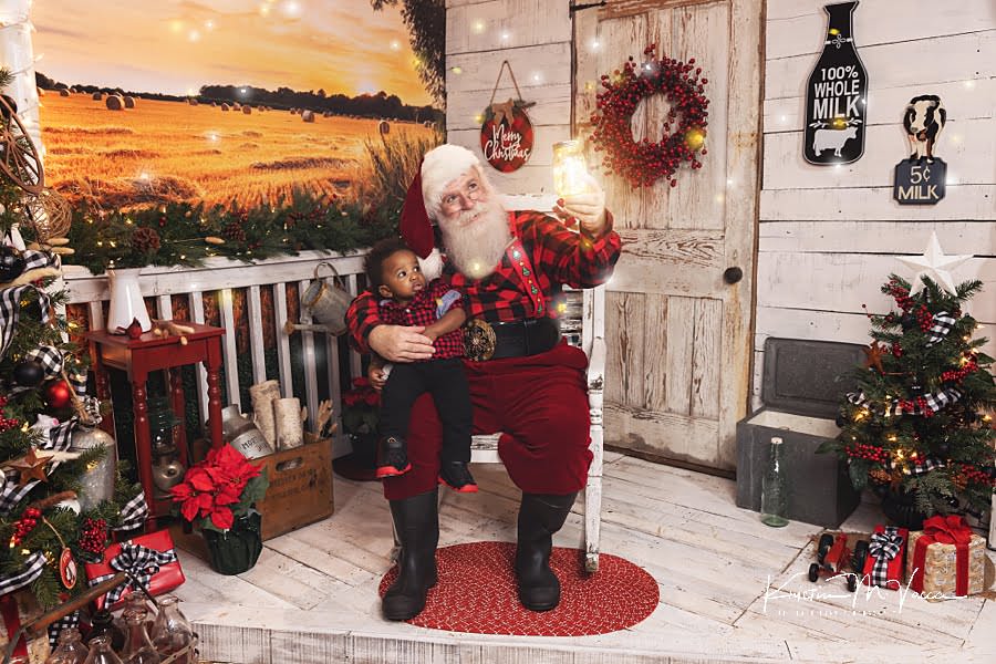 Santa Claus looks at a magical jar with fireflies with a baby during his photoshoot
