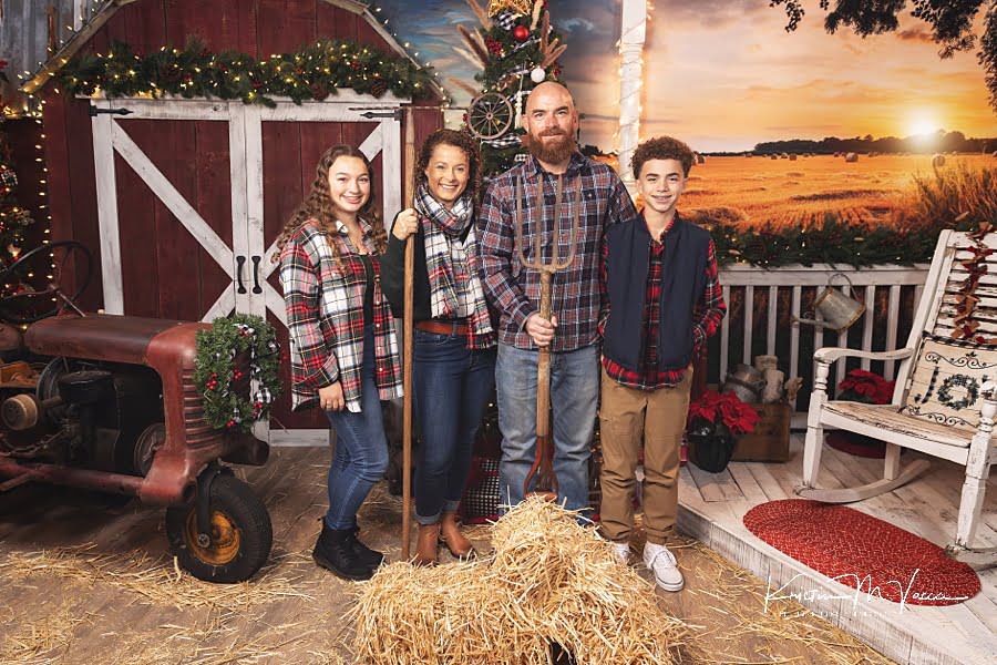 Family of 4 holds farm tools during their Christmas photos 2022 at The Flash Lady Photography