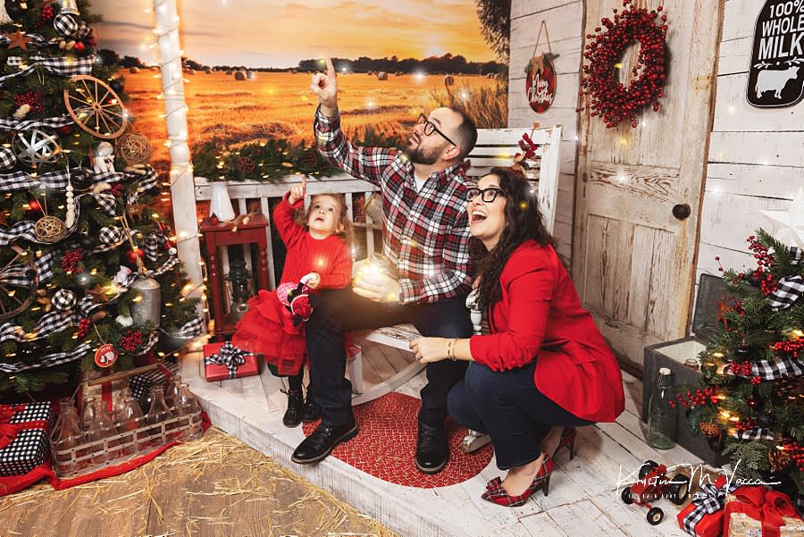 Family of 3 looks up at magical fireflies during their Christmas photos 2022 at The Flash Lady Photography