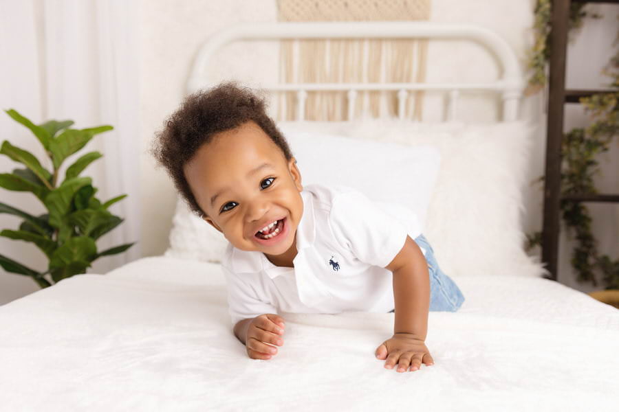 Smiling black baby boy on a bed during his first birthday milestone photos