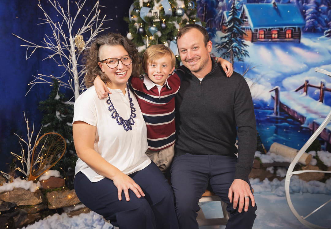 Mom & Dad pose with their son during their family Christmas photos